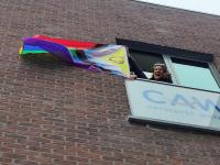 Melanie hangt regenboogvlag uit aan CAW gebouw